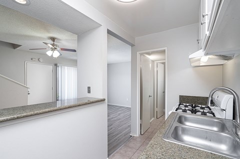 a kitchen with a sink and a stove and a ceiling fan